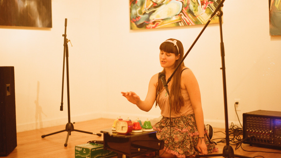 Alexa Dexa sits on the floor in Austin, TX playing their toy piano, desk bells, and an alarm clock.