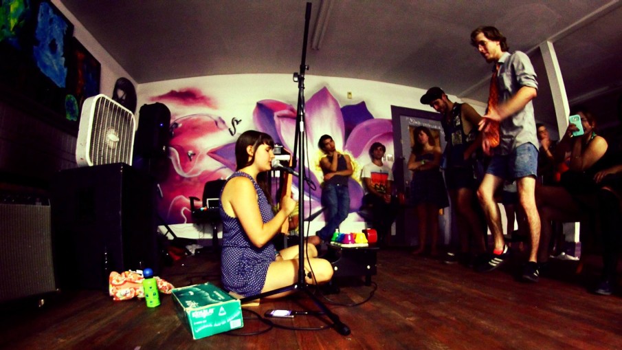 Alexa Dexa sits on the floor with their toy piano and desk bells playing a live show for the DIY crowd in Houston.