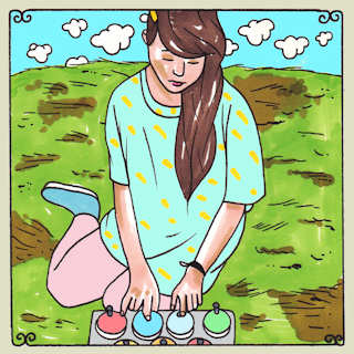 Daytrotter's cartoon of Alexa Dexa sitting on the earth playing her pitched desk bells.